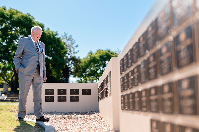 Visitor standing among memorial walls engraved with the names of Australian service personnel.