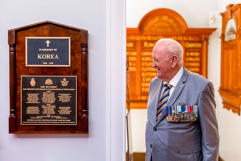 Veteran viewing a memorial plaque dedicated to service in the Korean War.