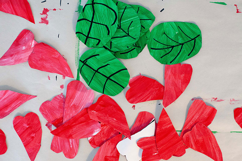Handmade red poppy petals and green leaves prepared for a remembrance wreath craft activity.