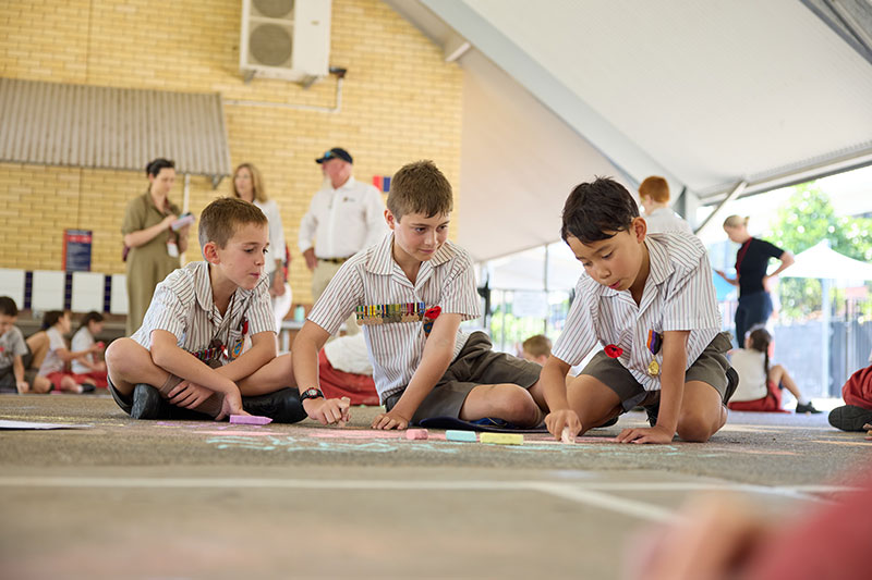 School students creating remembrance-themed chalk artwork during a Draw to Remember activity.