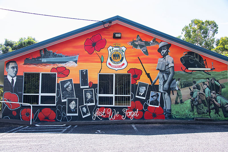 Building mural featuring military service personnel, wartime imagery and red poppies with the words “Lest We Forget”. Cardwell RSL Sub Branch