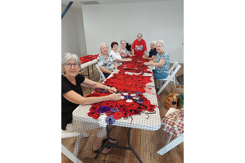 Sandgate QCWA Branch members assembling handmade poppy panels for a community remembrance display.