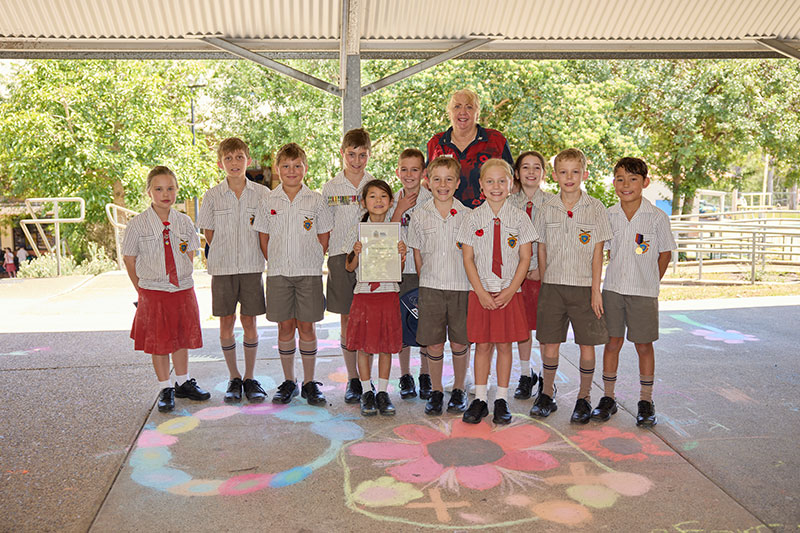 Primary school students standing beside their completed remembrance artwork and certificate.
