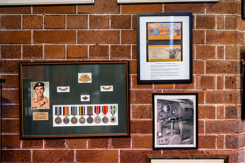 Military medals, photographs and service memorabilia displayed on a museum wall.